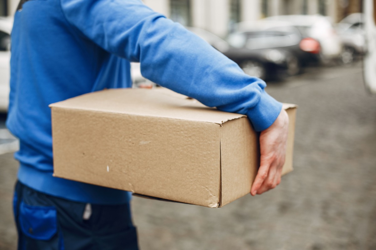 Courier carrying a parcel while moving through a city street.